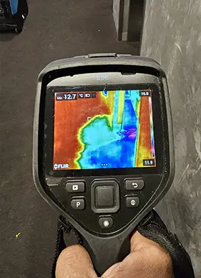 Technician using moisture meter to assess water damage in carpet underlay